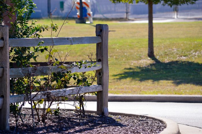 The corner of a street with mulch and a wooden fence